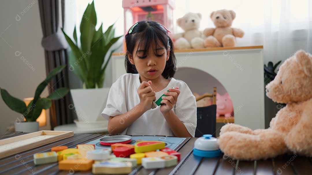 Menina asiática brincando com blocos de quebra-cabeça coloridos em casa