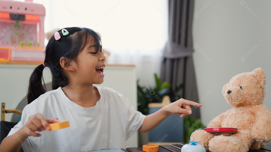 Menina asiática brincando com blocos de quebra-cabeça coloridos em casa
