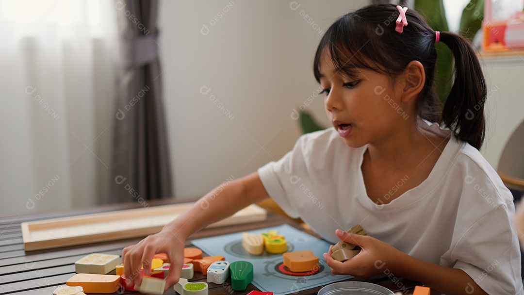 Menina asiática brincando com blocos de quebra-cabeça coloridos em casa