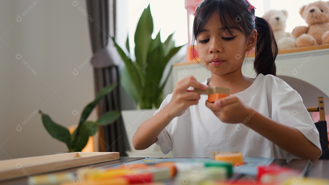 Menina asiática brincando com blocos de quebra-cabeça coloridos em casa