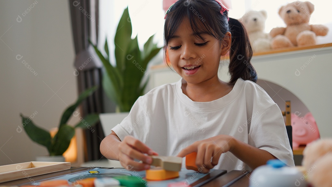 Menina asiática brincando com blocos de quebra-cabeça coloridos em casa