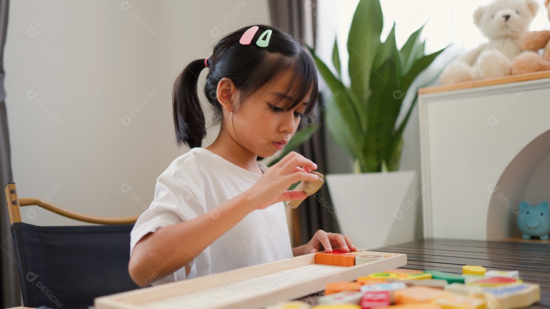 Menina asiática brincando com blocos de quebra-cabeça coloridos em casa