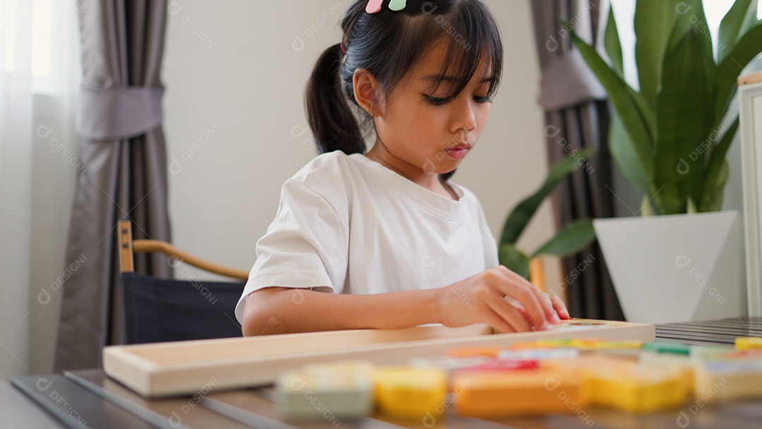 Menina asiática brincando com blocos de quebra-cabeça coloridos em casa