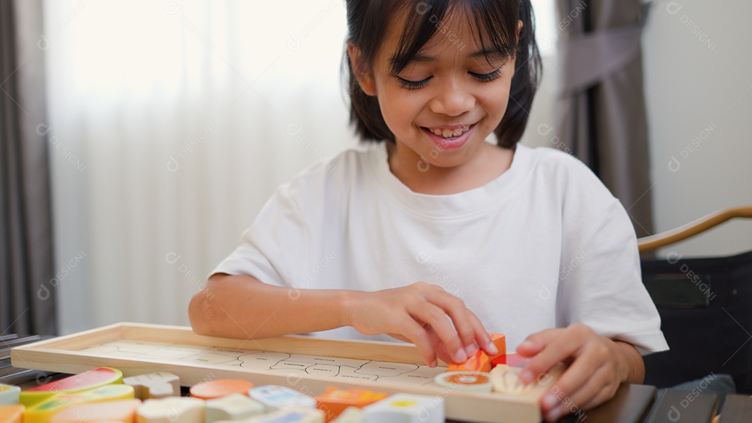 Menina asiática brincando com blocos de quebra-cabeça coloridos em casa