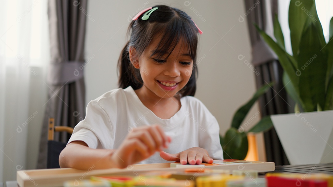 Menina asiática brincando com blocos de quebra-cabeça coloridos em casa