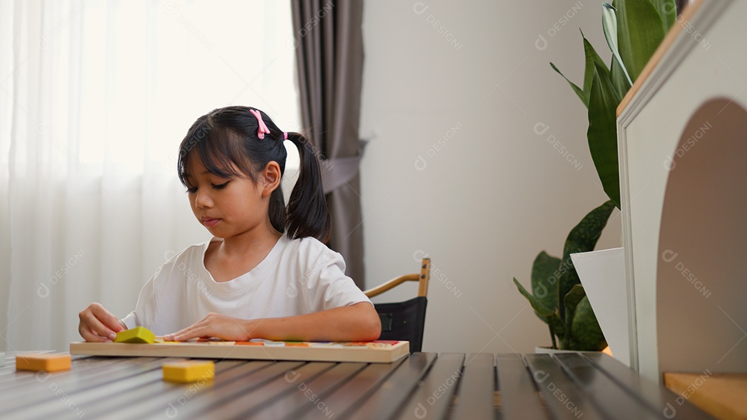 Menina asiática brincando com blocos de quebra-cabeça coloridos em casa