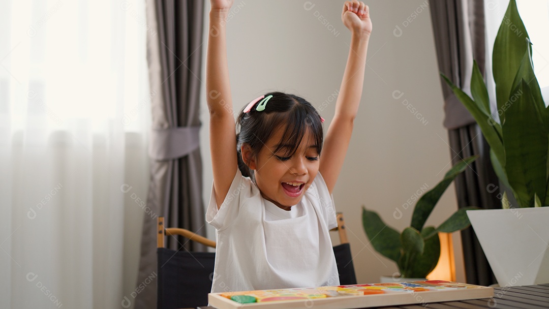 Menina asiática brincando com blocos de quebra-cabeça coloridos em casa