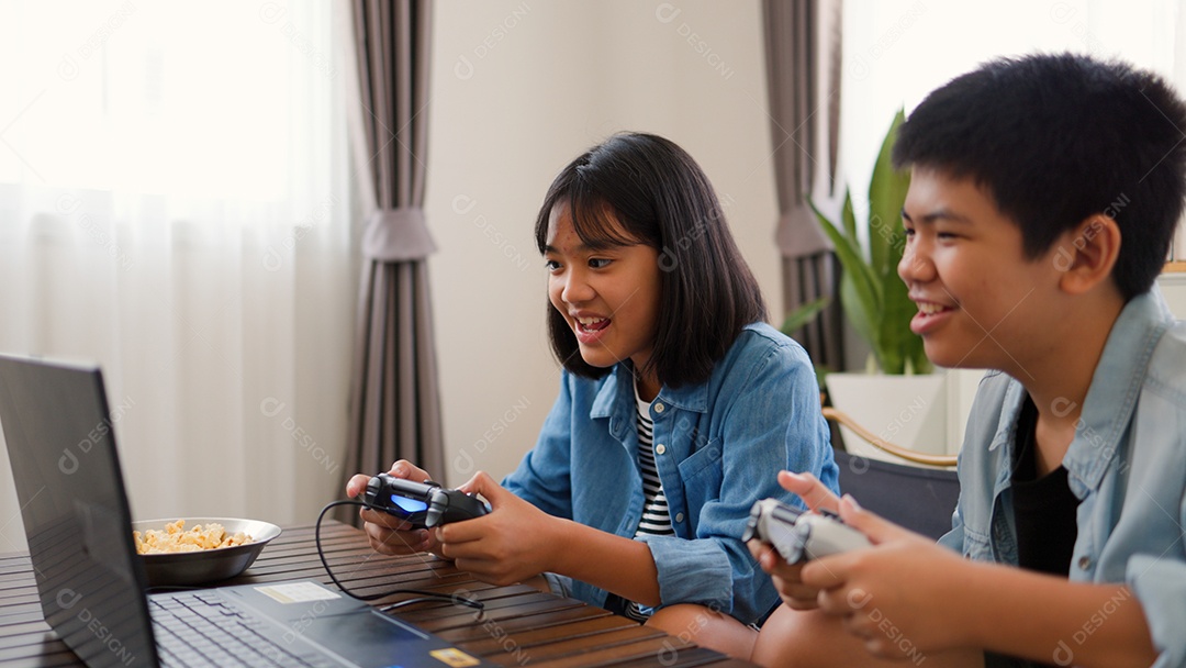 Adolescente asiático e menina jogando videogame juntos em casa