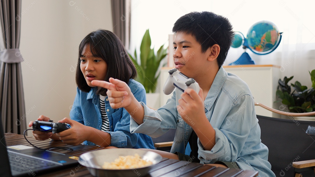 Adolescente asiático e menina jogando videogame juntos em casa
