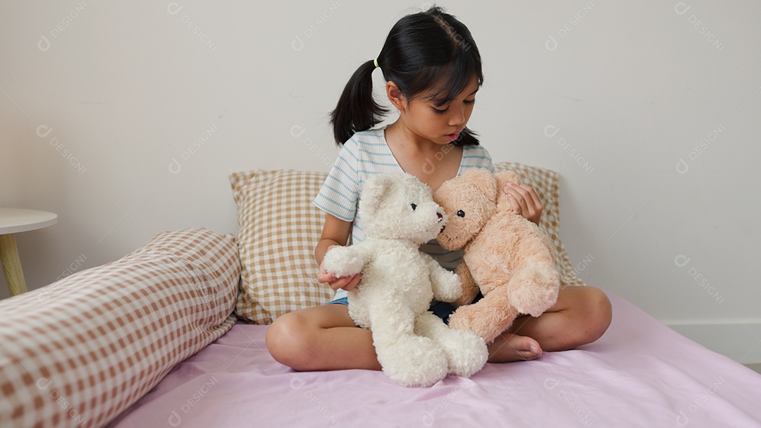 Linda garota asiática brincando com ursinhos de pelúcia na cama em um quarto aconchegante