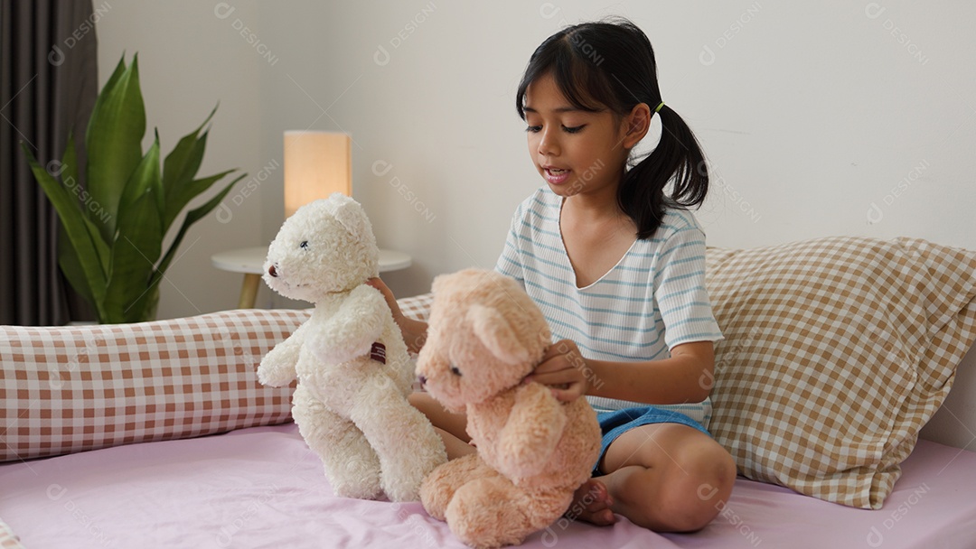 Linda garota asiática brincando com ursinhos de pelúcia na cama em um quarto aconchegante