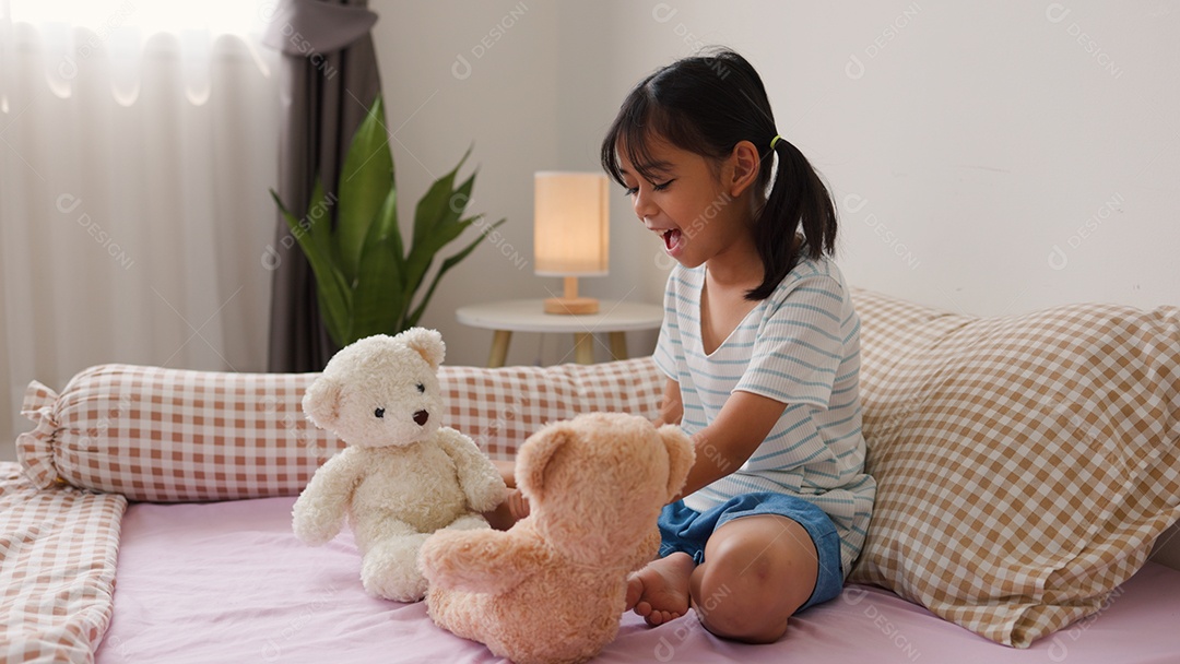 Linda garota asiática brincando com ursinhos de pelúcia na cama em um quarto aconchegante