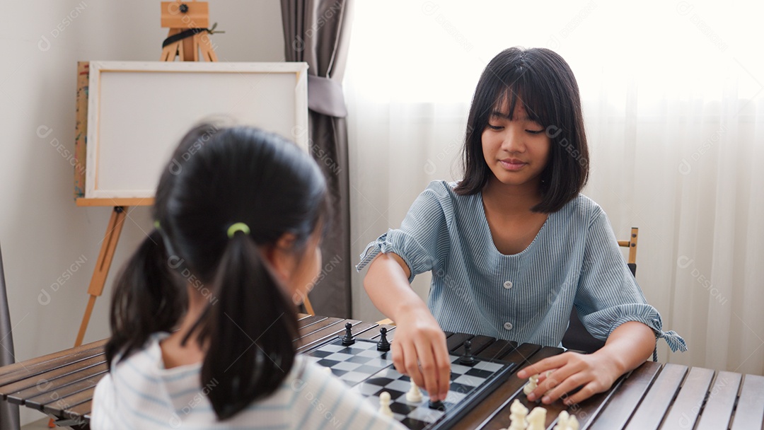 Duas garotas asiáticas jogando xadrez em casa