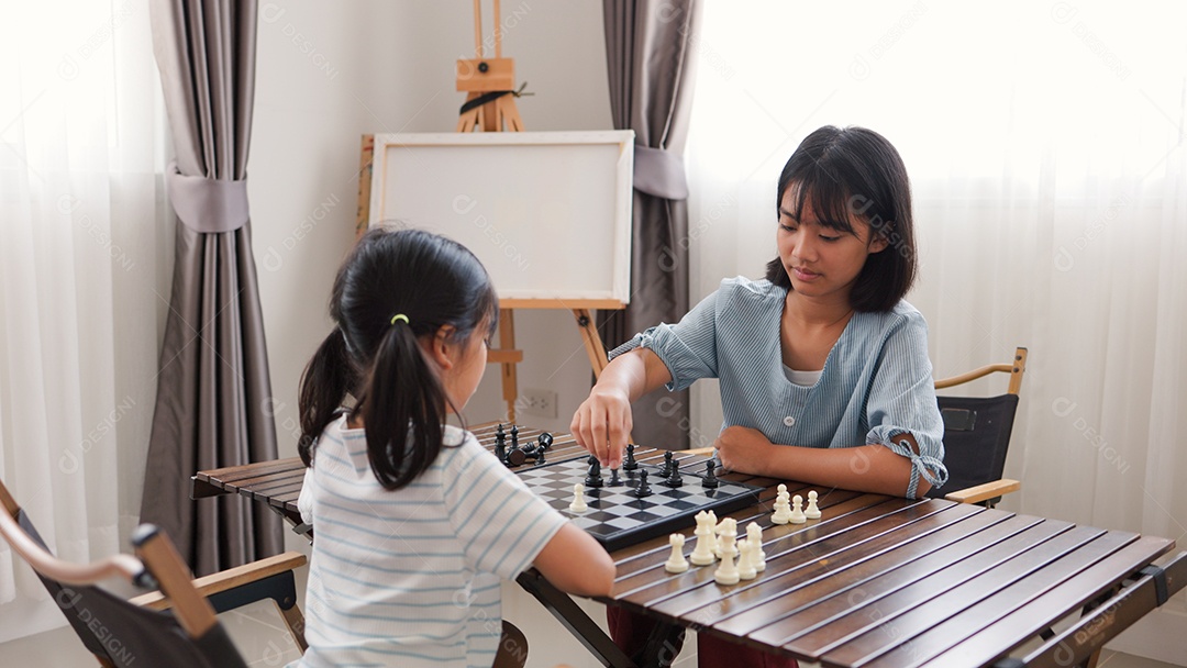 Duas garotas asiáticas jogando xadrez em casa
