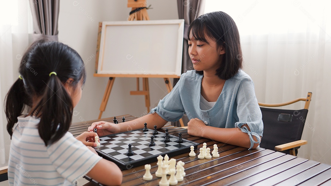 Duas garotas asiáticas jogando xadrez em casa
