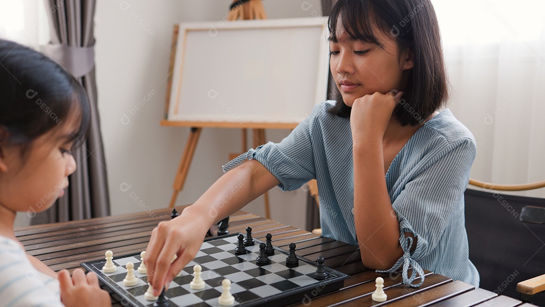 Duas garotas asiáticas jogando xadrez em casa