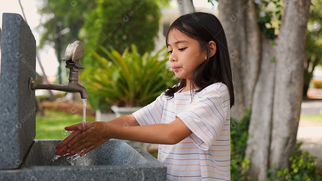 Menina asiática lavando as mãos na pia ao ar livre