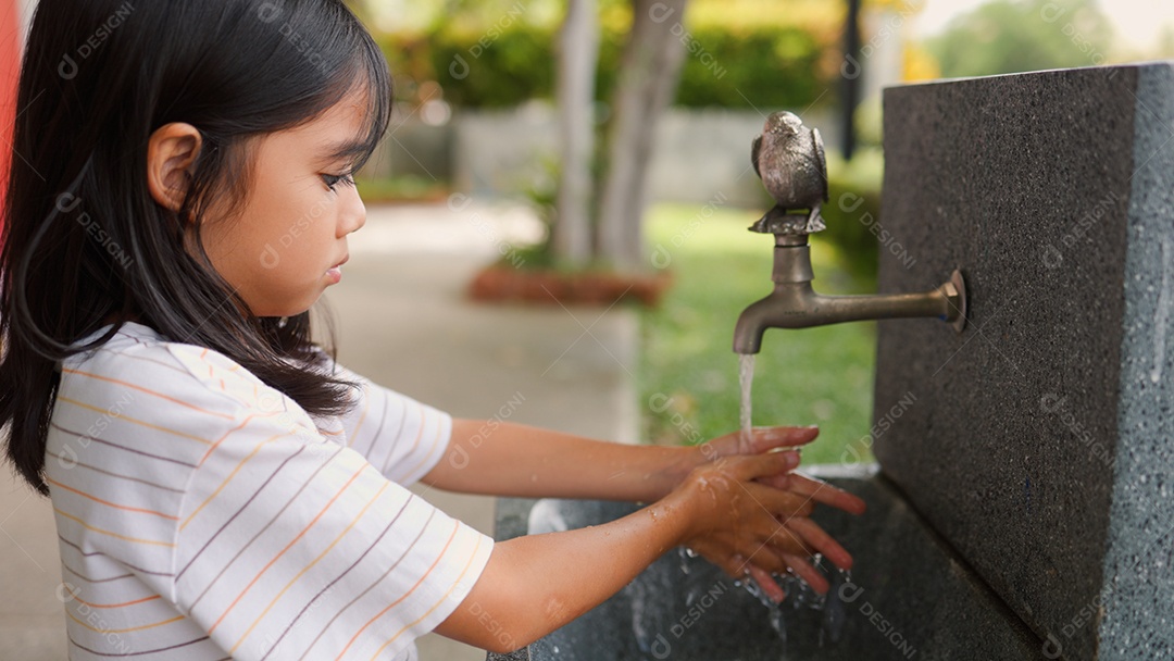 Menina asiática lavando as mãos na pia ao ar livre