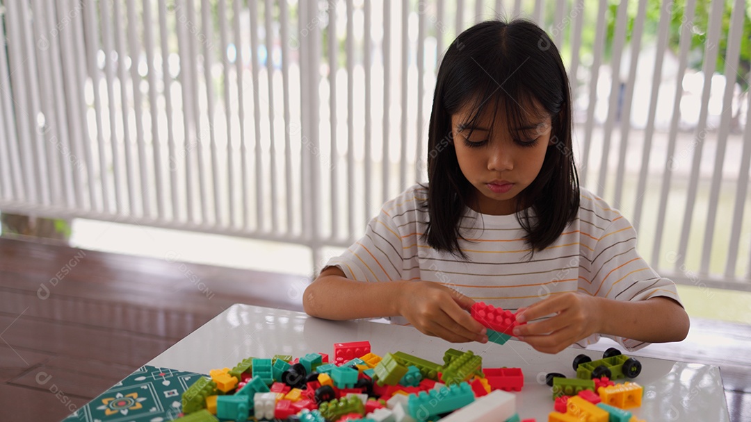 Menina asiática brincando com blocos de construção coloridos em casa