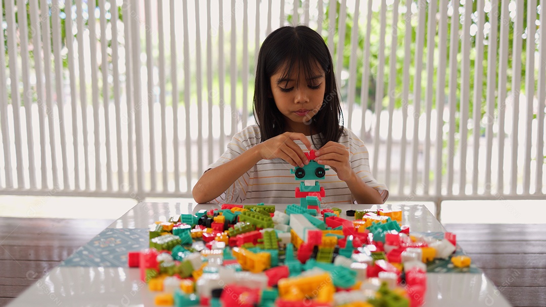 Menina asiática brincando com blocos de construção coloridos em casa