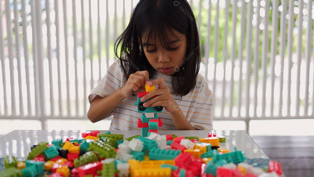 Menina asiática brincando com blocos de construção coloridos em casa