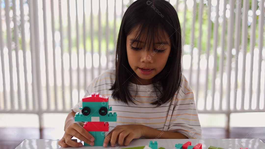 Menina asiática brincando com blocos de construção coloridos em casa