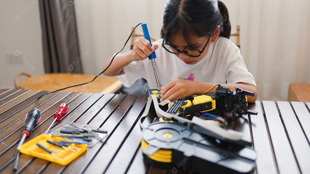 Garota asiática montando peças de robô em casa