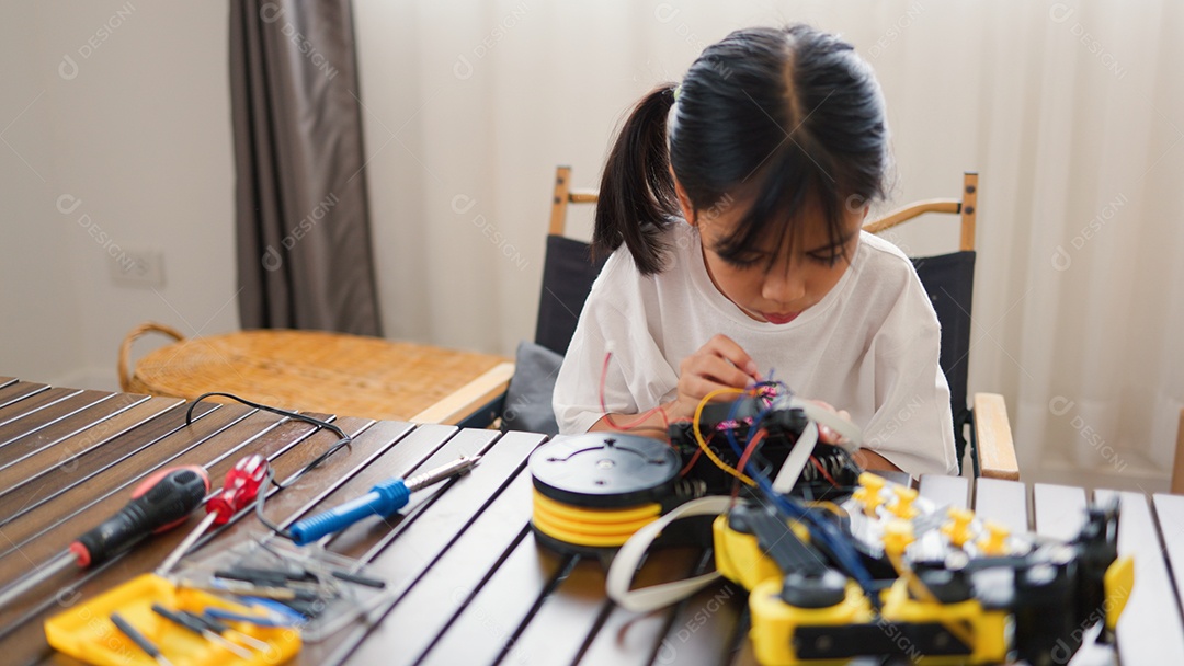 Garota asiática montando peças de robô em casa