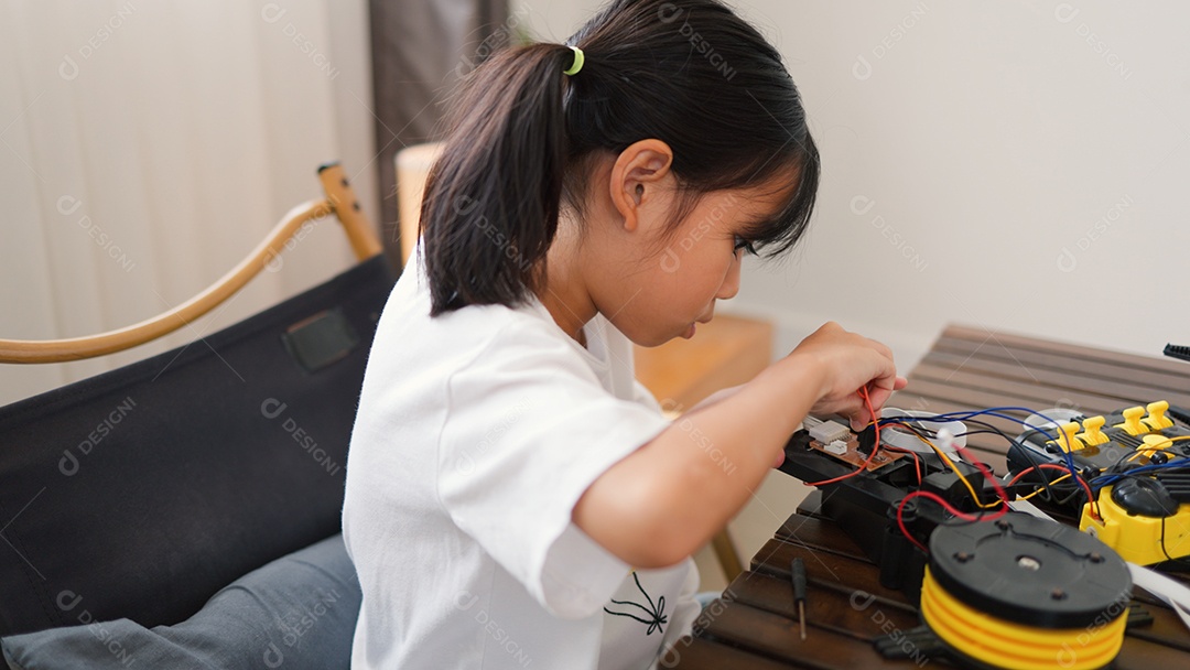 Garota asiática montando peças de robô em casa