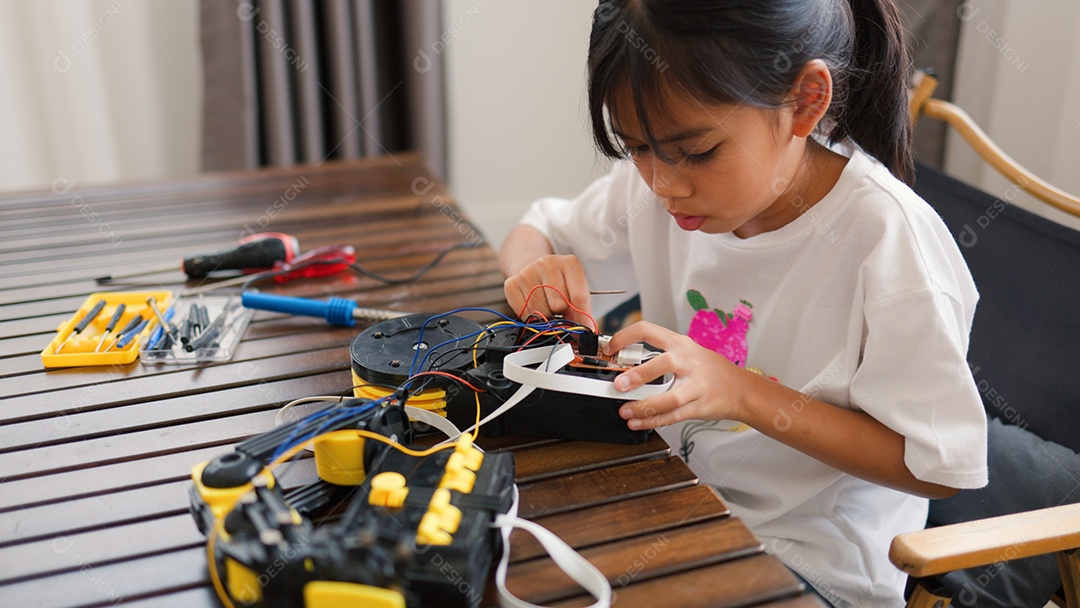 Garota asiática montando peças de robô em casa