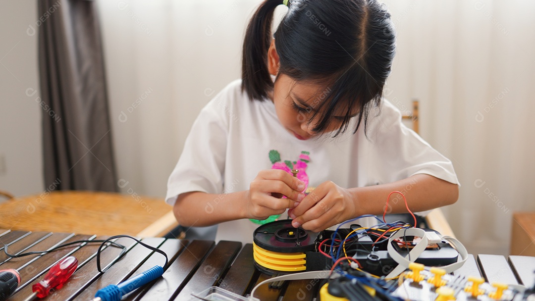 Garota asiática montando peças de robô em casa