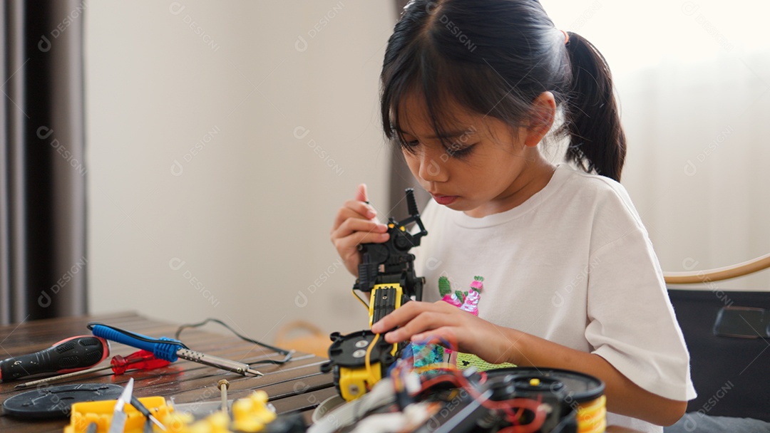 Garota asiática montando peças de robô em casa