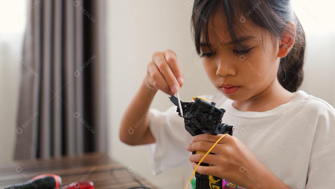 Garota asiática montando peças de robô em casa