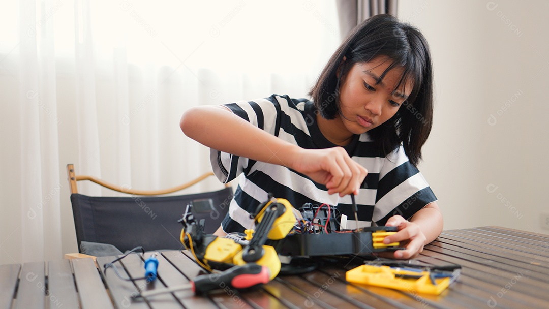 Garota asiática montando peças de robô em casa