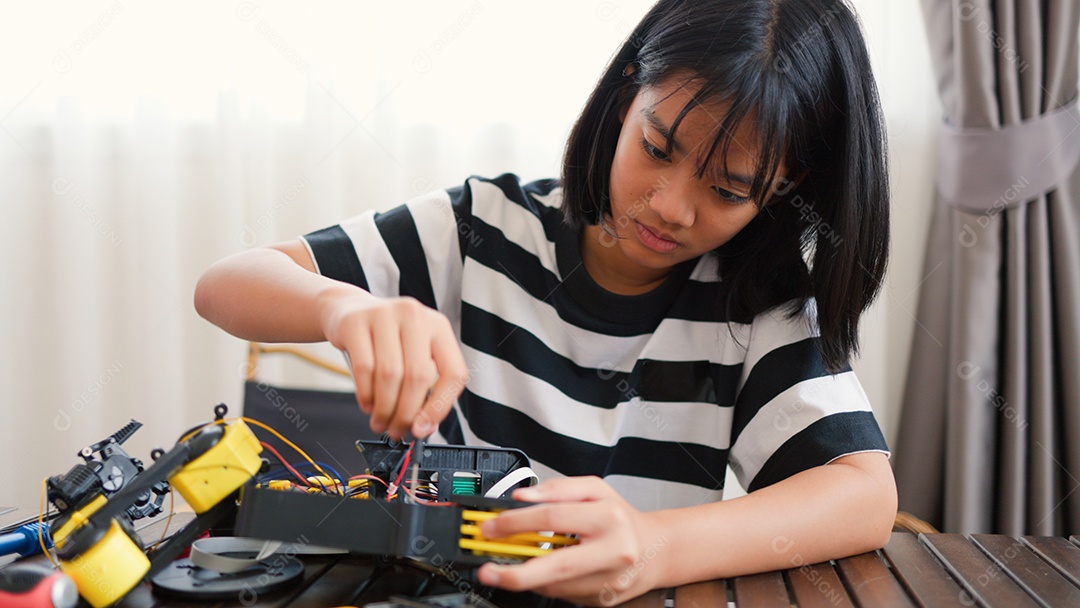 Garota asiática montando peças de robô em casa
