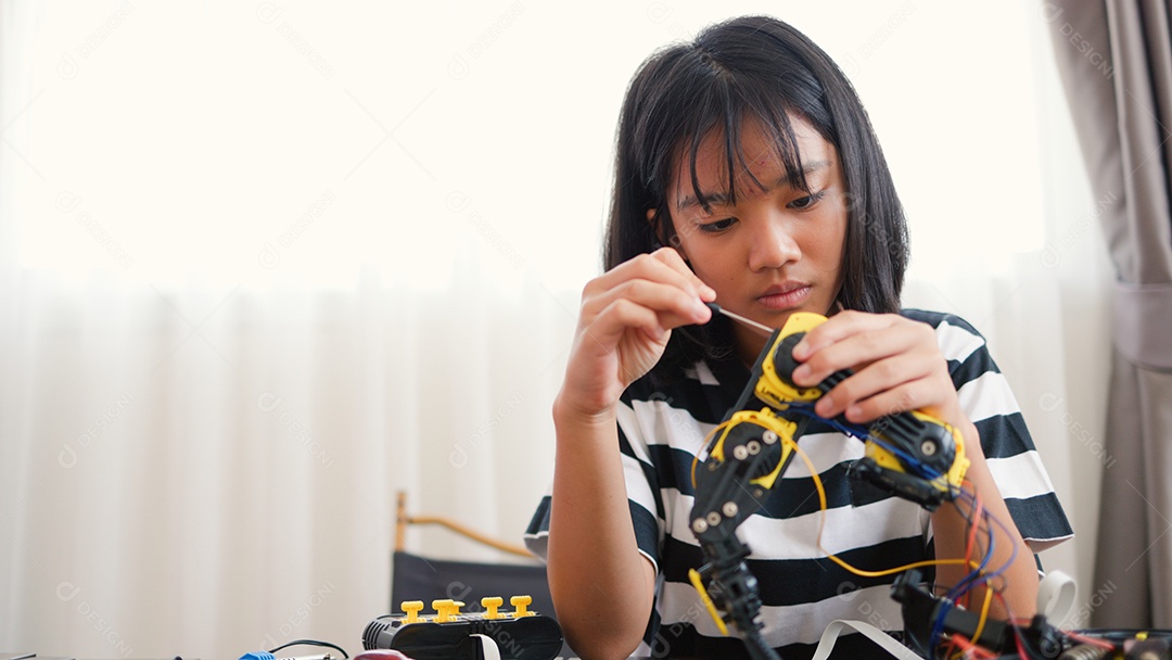 Garota asiática montando peças de robô em casa