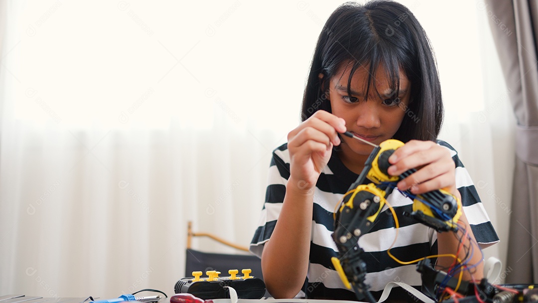 Garota asiática montando peças de robô em casa