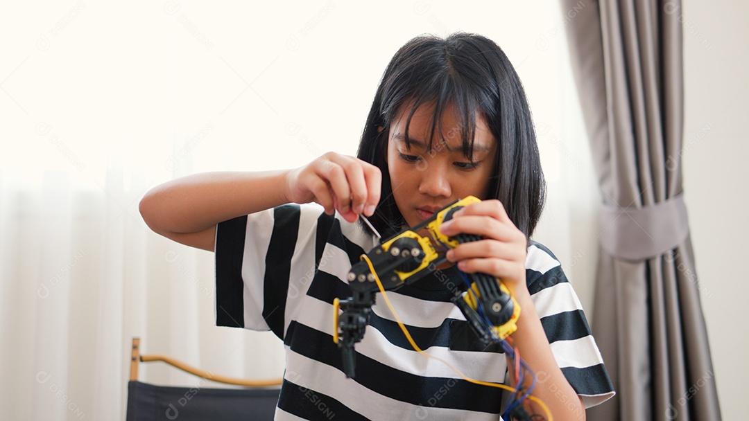 Garota asiática montando peças de robô em casa