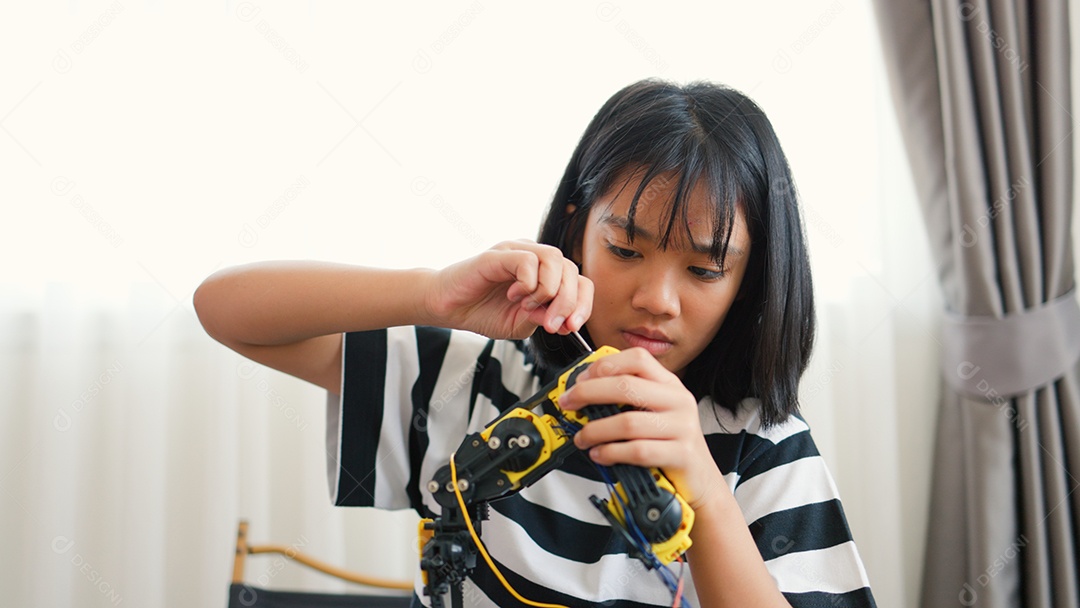 Garota asiática montando peças de robô em casa