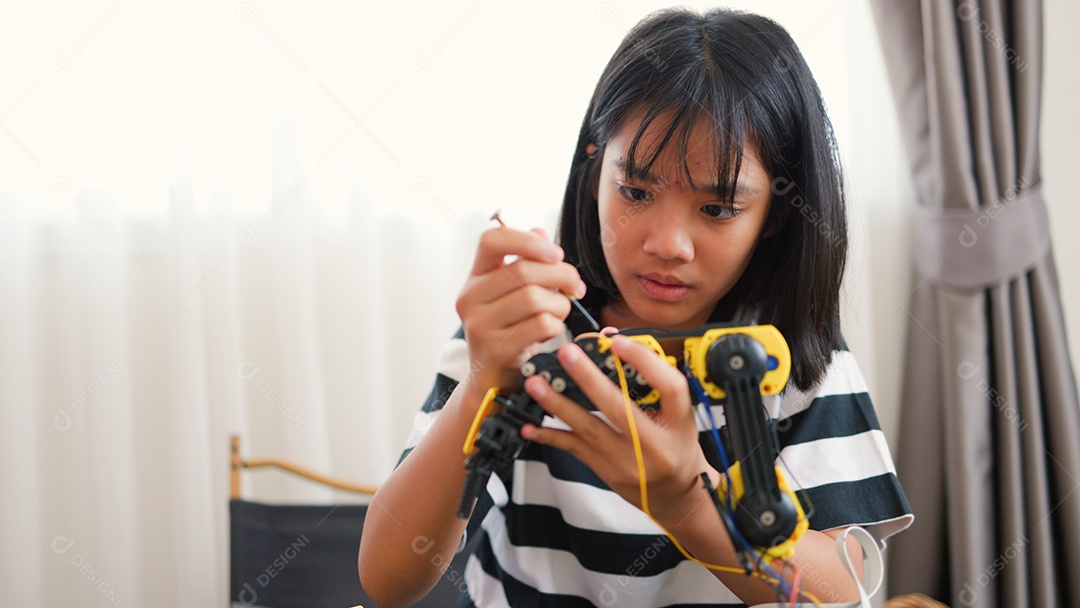 Garota asiática montando peças de robô em casa