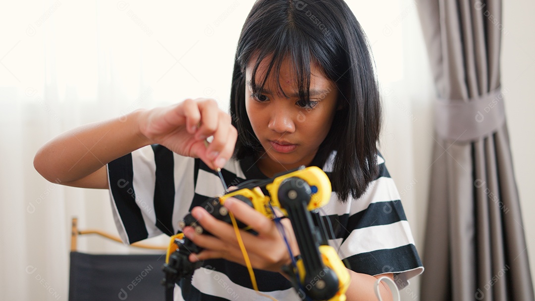 Garota asiática montando peças de robô em casa