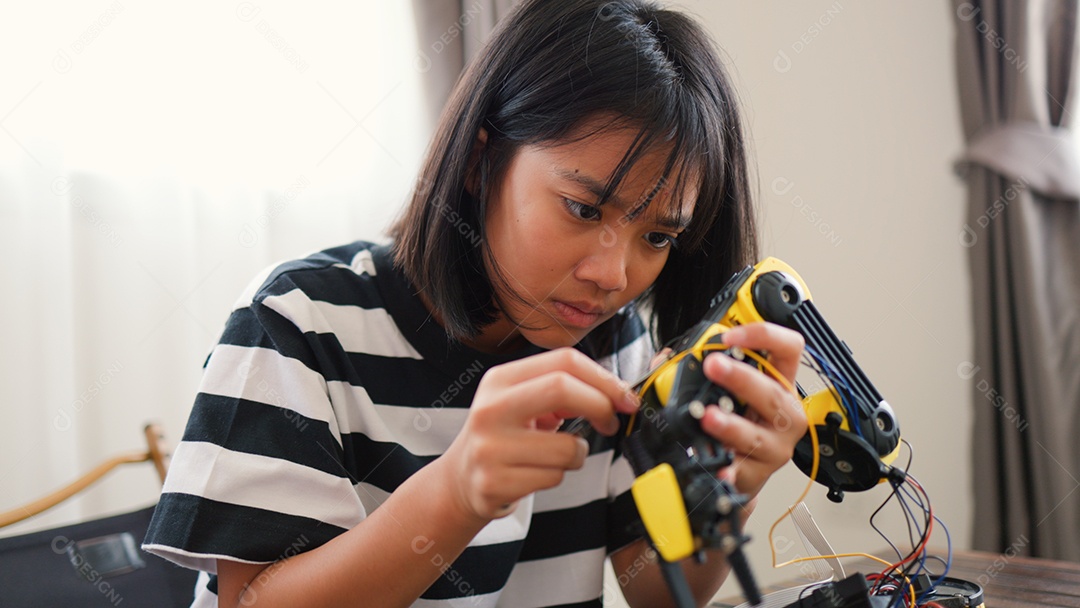 Garota asiática montando peças de robô em casa