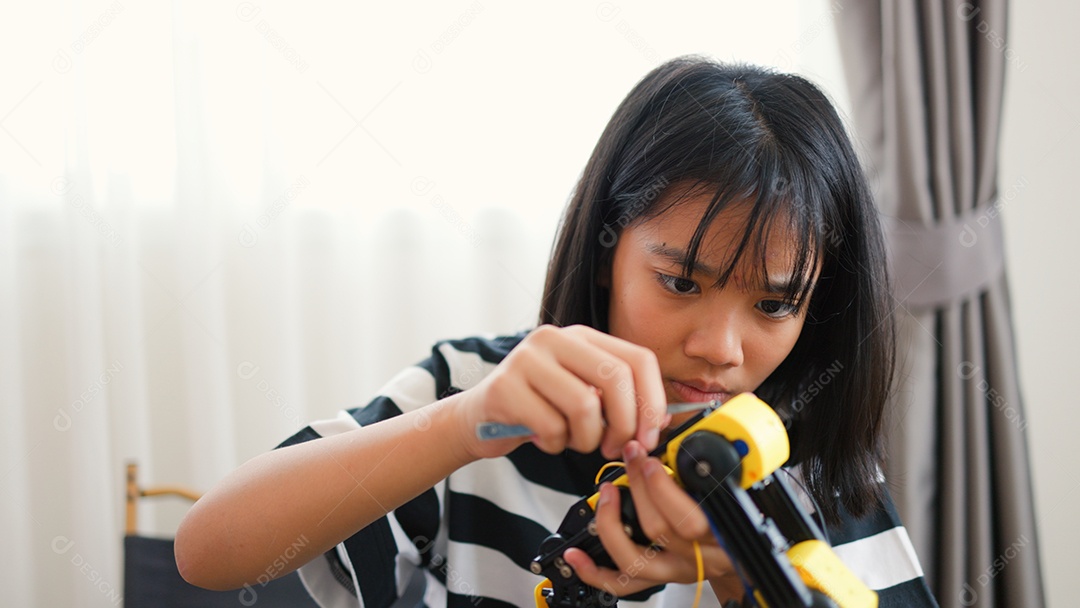 Garota asiática montando peças de robô em casa