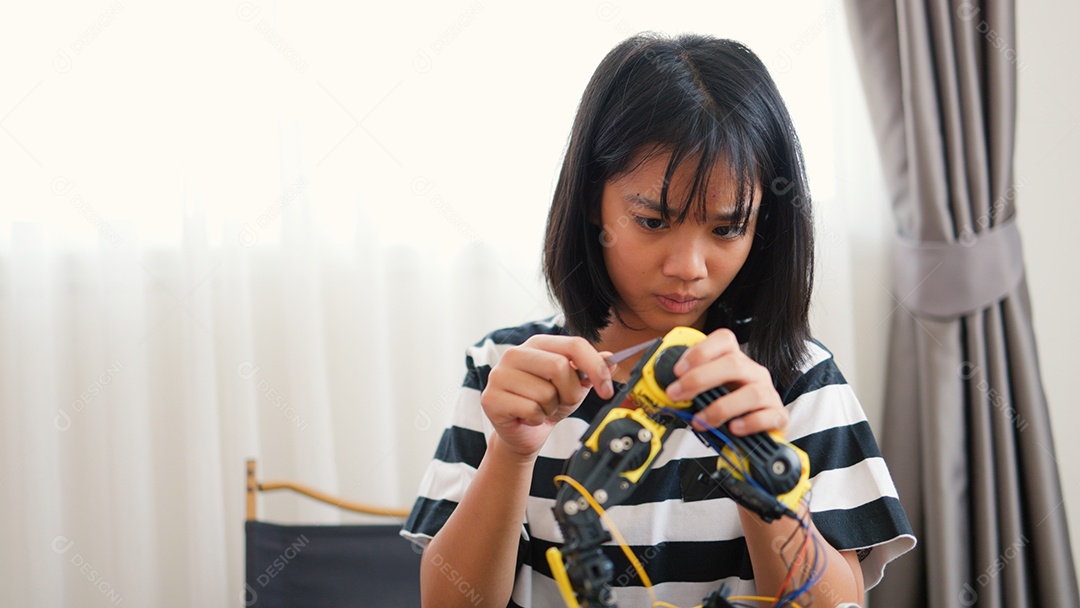 Garota asiática montando peças de robô em casa