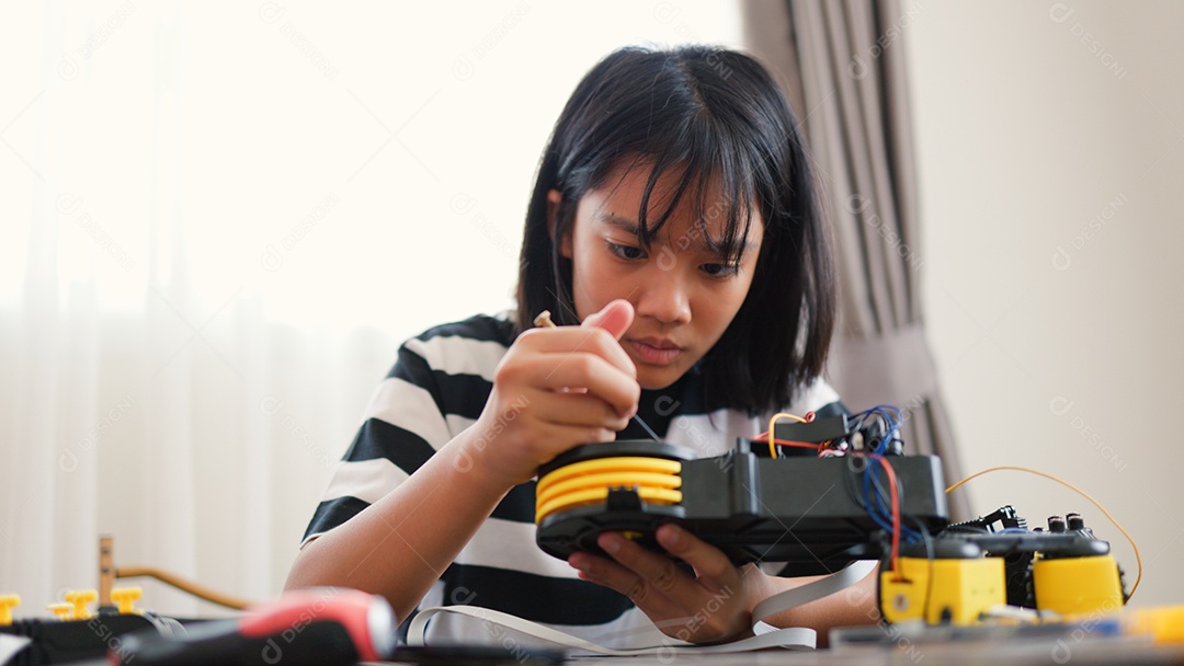 Garota asiática montando peças de robô em casa