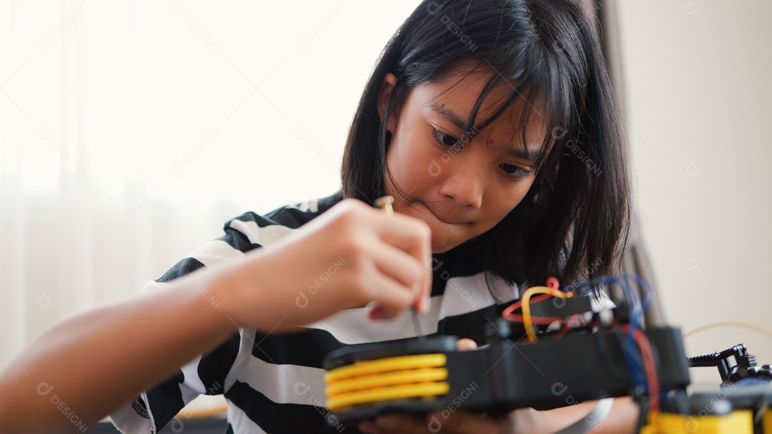 Garota asiática montando peças de robô em casa