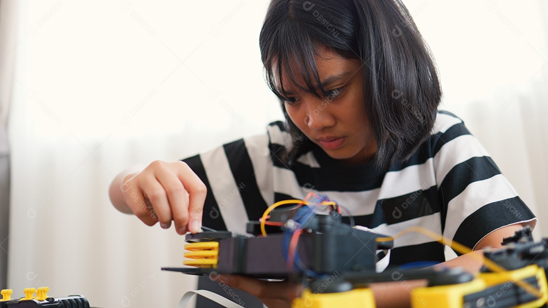 Garota asiática montando peças de robô em casa