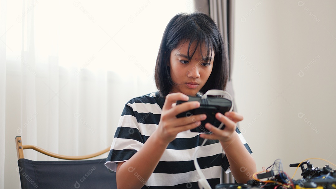 Garota asiática montando peças de robô em casa