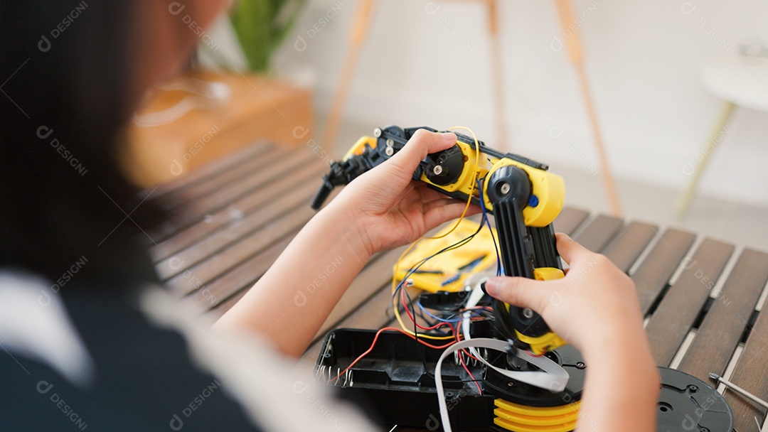 Garota asiática montando peças de robô em casa