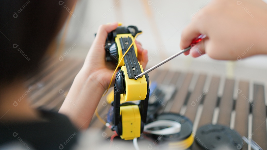 Garota asiática montando peças de robô em casa